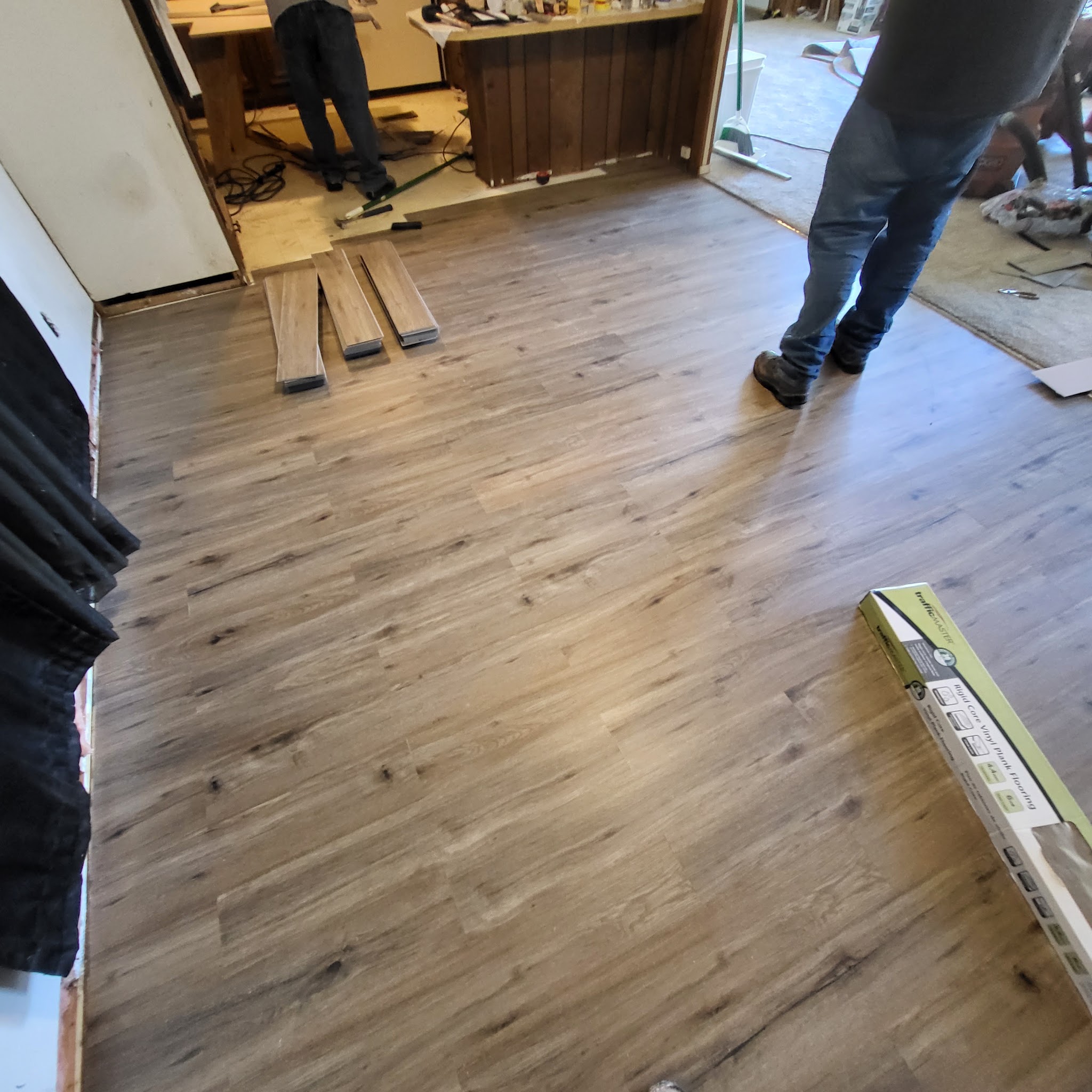 Vinyl plank flooring being installed across a living room